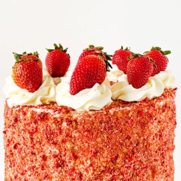 Top of cake decorated with swirls of buttercream and fresh strawberries. 