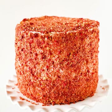 Iced cake covered in pink crunchy topping. 
