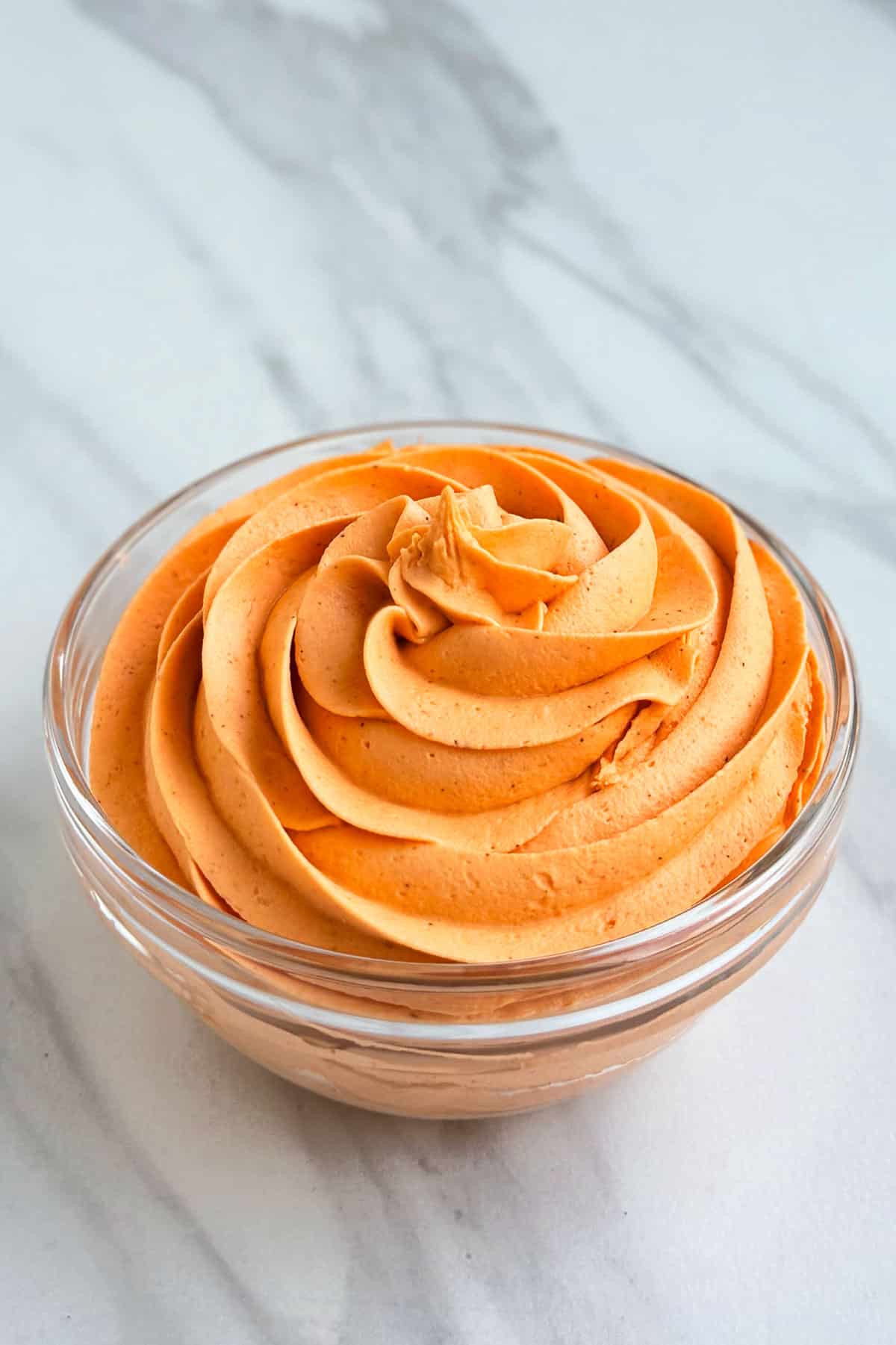 Easy Spiced Pumpkin Frosting With Cream Cheese and Pumpkin Puree in Glass Bowl on White Marble Background. 