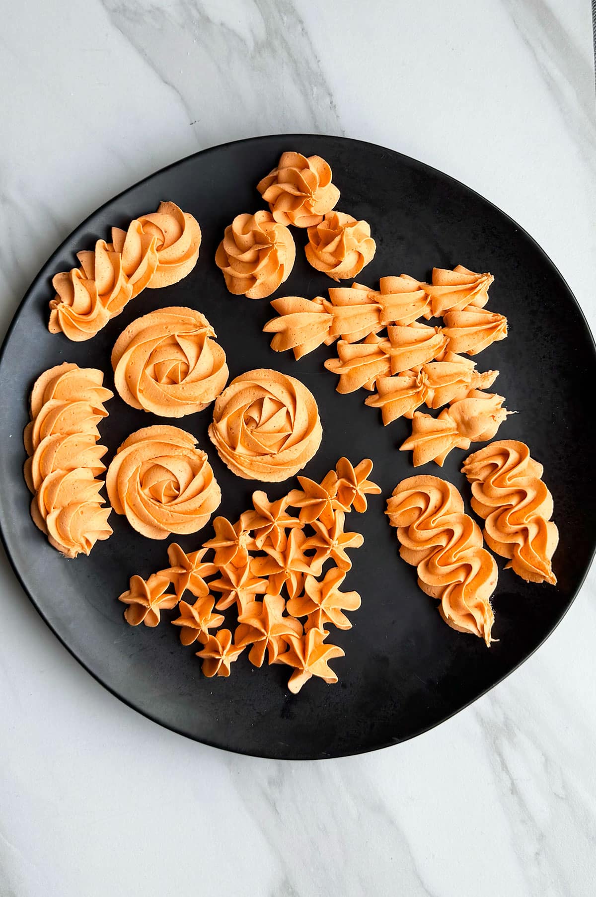 Piped frosting designs on a black dish. 