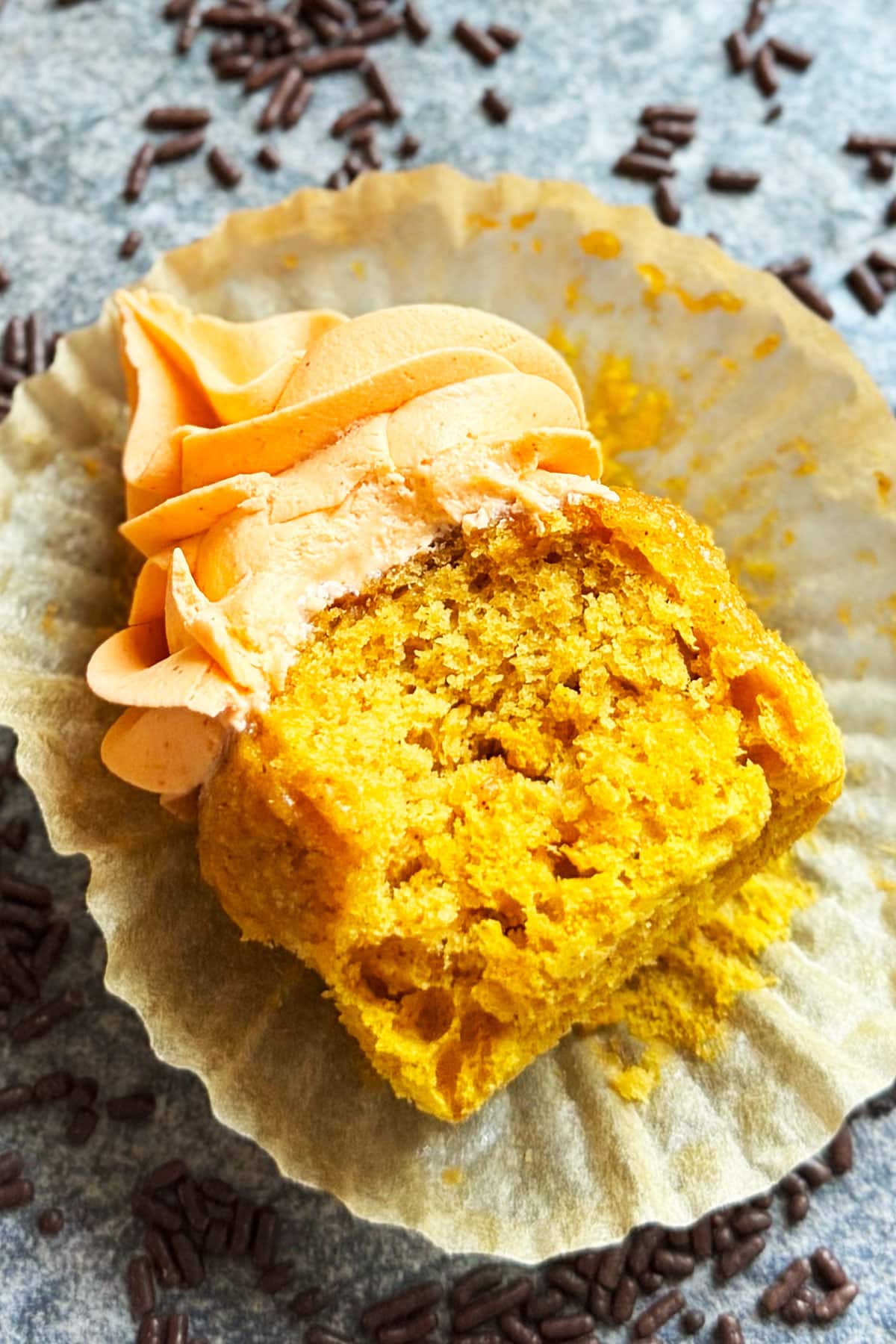 Partially eaten cupcake on peeled liner. 