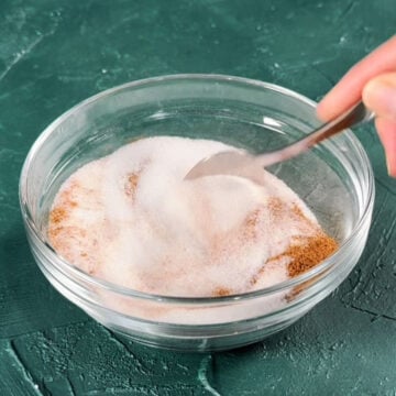 Ingredients being mixed together with spoon in glass bowl. 