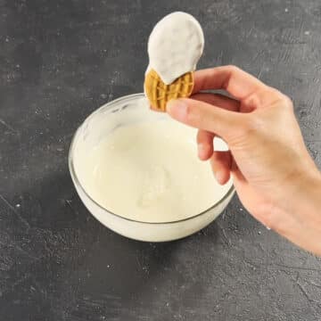 Excess white chocolate being dripped off a cookie. 