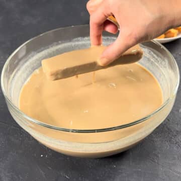 Cake rusk being dipped in a bowl of chai tea. 