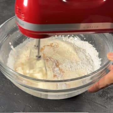 Heavy cream, chai spice mix and powdered sugar being whipped in a glass bowl. 