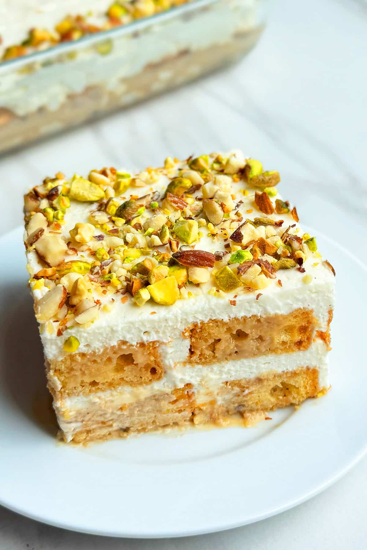 Slice of Easy No Bake Masala Spiced Chai Tiramisu Cake on White Dish.
