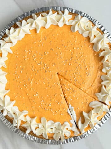 Easy No Bake Pumpkin Pie on White Marble Background With a Slice Cut Out.