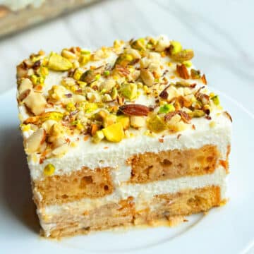 Slice of Easy No Bake Masala Spiced Chai Tiramisu Cake With Cake Rusks on White Dish.