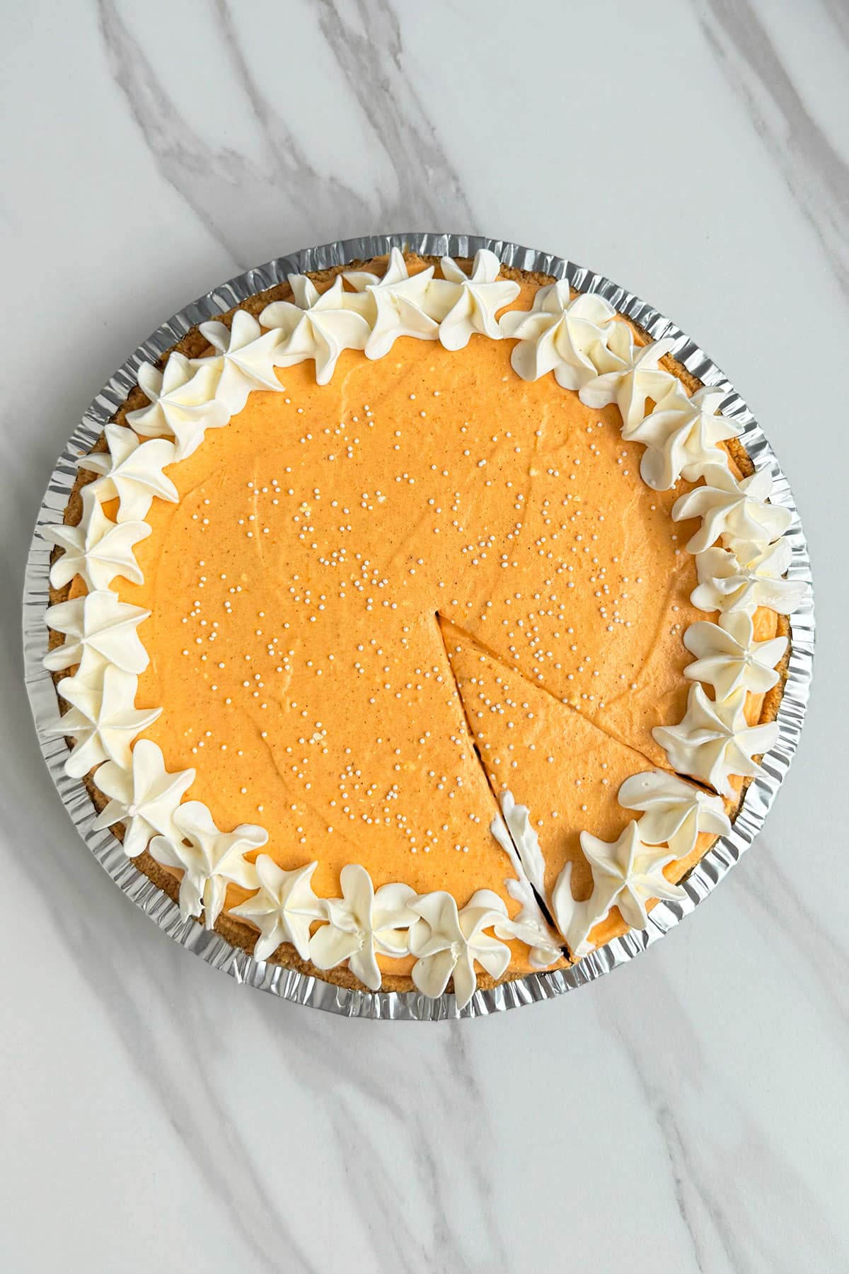 Easy No Bake Pumpkin Pie on White Marble Background With a Slice Cut Out. 