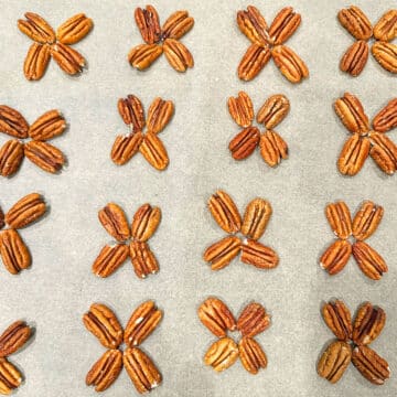 Pecan halves arranged in clusters of four on sheet of wax paper. 