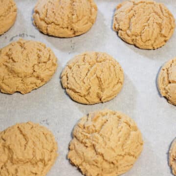 Baked cookies in lined tray removed from oven and cooling. 