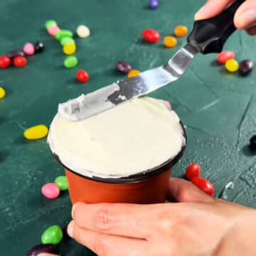 Top of the cupcake being iced smoothly with a spatula. 