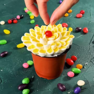 Red jelly bean being placed in the center of the final dessert. 