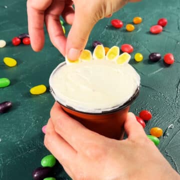 Sugar covered marshmallows being placed on top of frosting. 