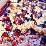 Partially eaten easy strawberry dump cake with cake mix in a rectangle stainless steel pan.