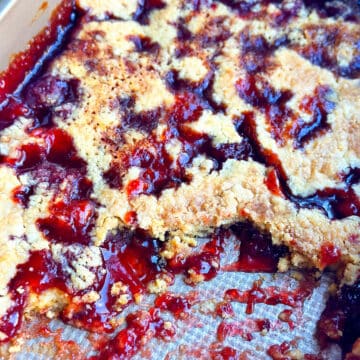 Partially eaten easy strawberry dump cake with cake mix in a rectangle stainless steel pan.