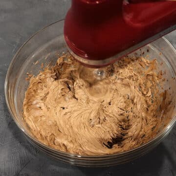 Ingredients being mixed together with a red hand held mixer.