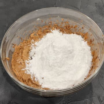 Powdered sugar added to chocolate mixture in glass bowl.