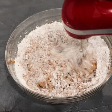 Powdered sugar and chocolate mixture being mixed together with red hand held mixer.