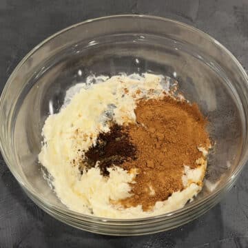 Cocoa powder, espresso powder, vanilla extract and milk added to creamed butter in glass bowl.