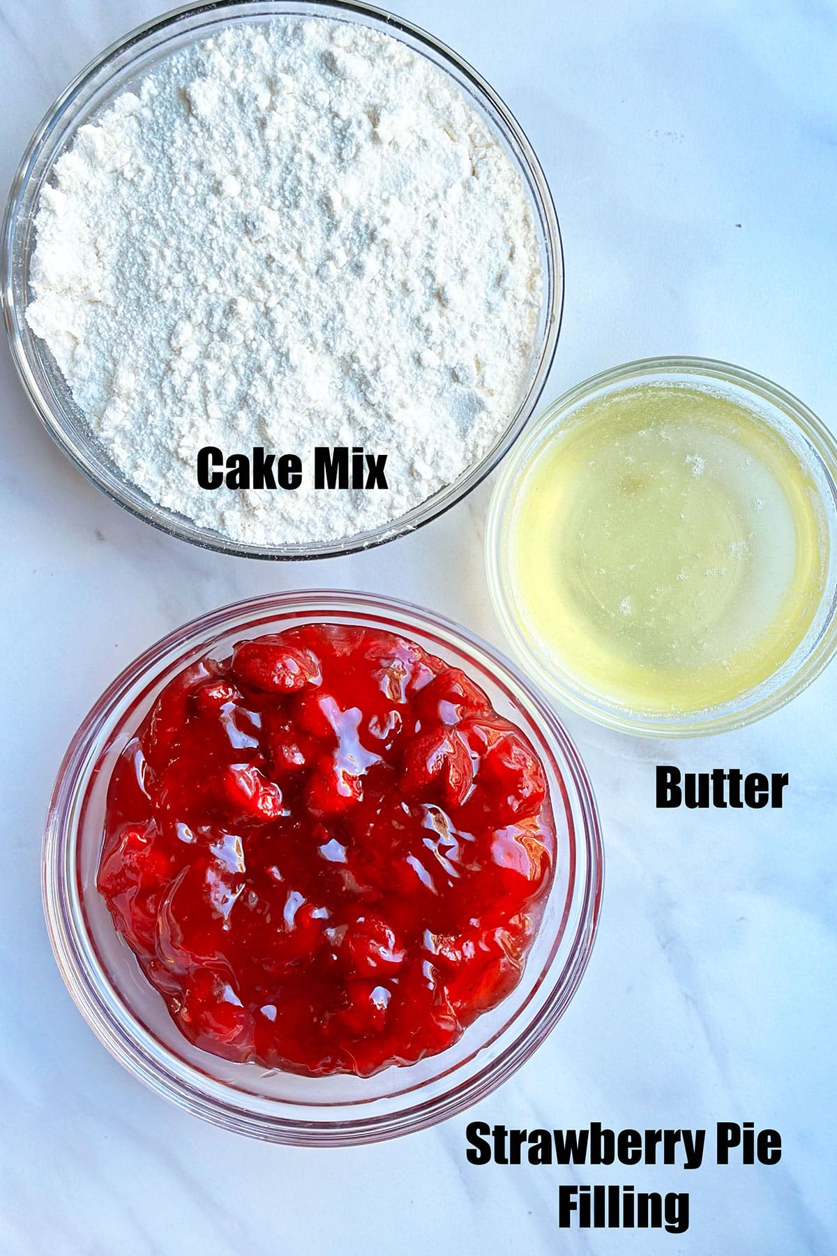 Ingredients in separate bowls on white marble background. 