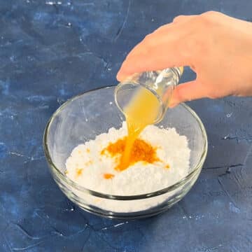 Powdered sugar, orange juice and zest in glass bowl. 