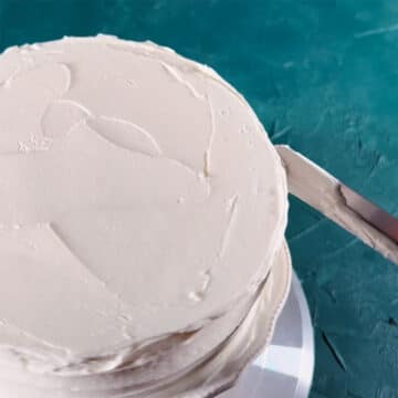 Spatula being used to create spiral design along sides of the cake. 
