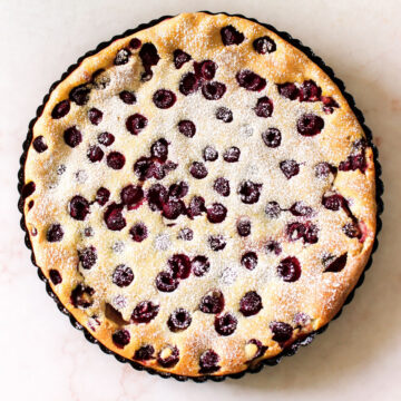 Baked custard cake with dusting of powdered sugar on marble background. 