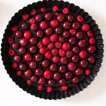 Raspberries and cherries spread evenly in a greased nonstick pan. 