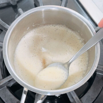 Melted butter foaming in saucepan over medium heat and being mixed with a spoon. 