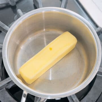 Block of butter in a stainless steel saucepan. 