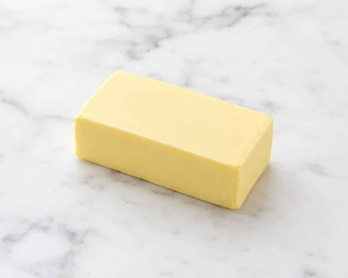 Block of butter on white marble background. 